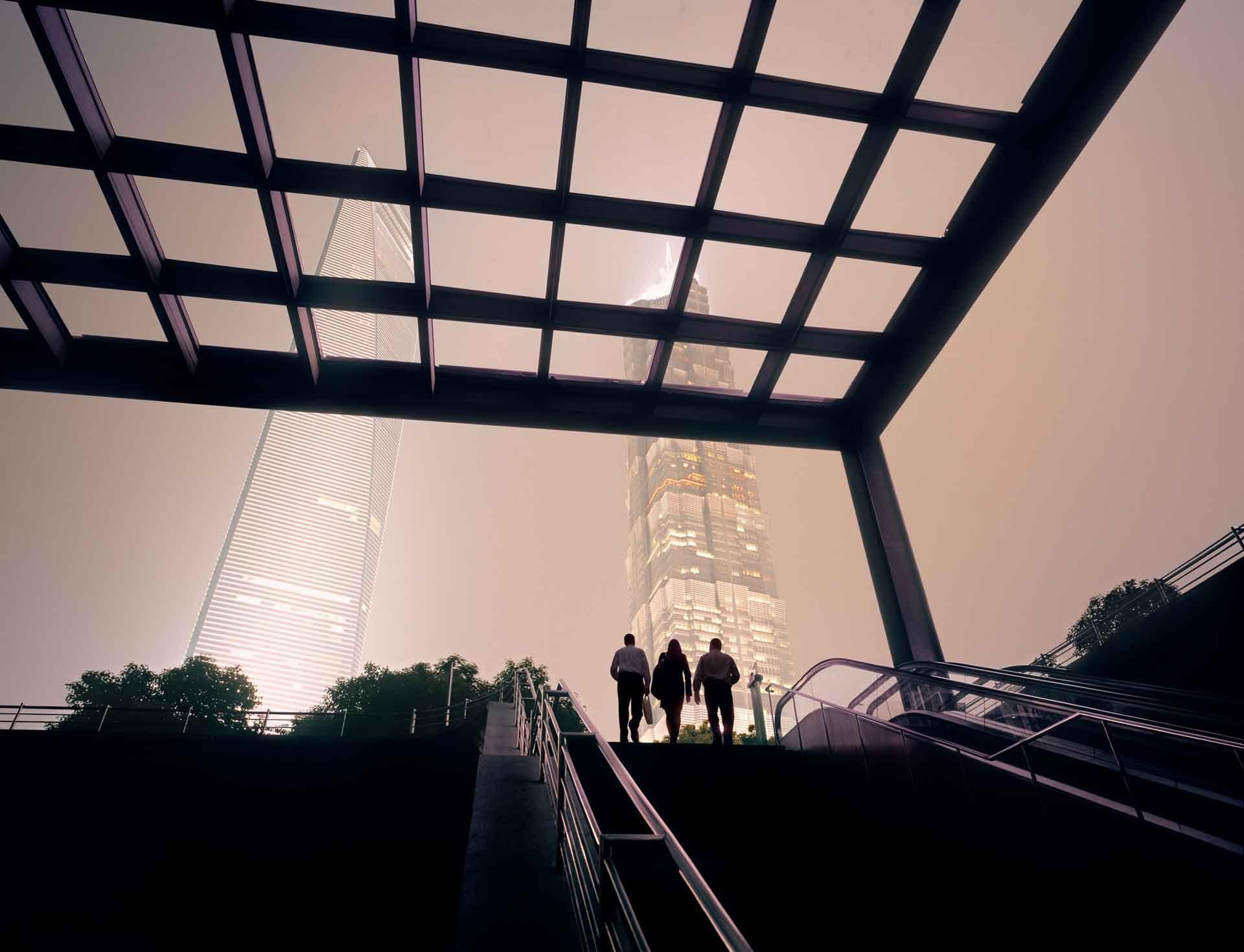 Three people on top of stairs outside looking at skyscrapers