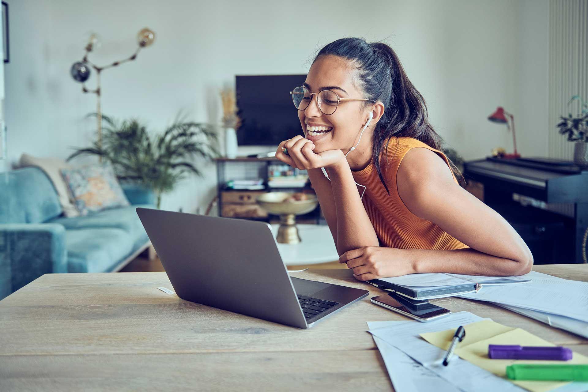 woman sitting in front of a laptop laughing