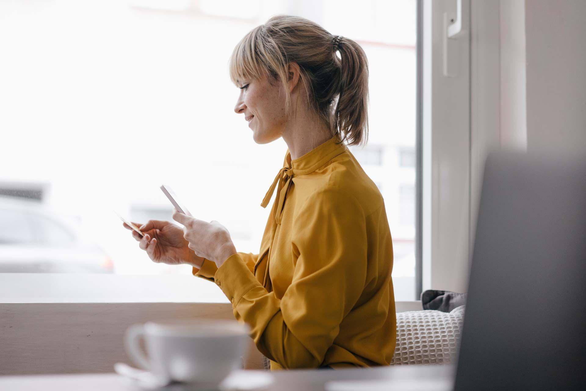 Woman in front of a window looking at her phone