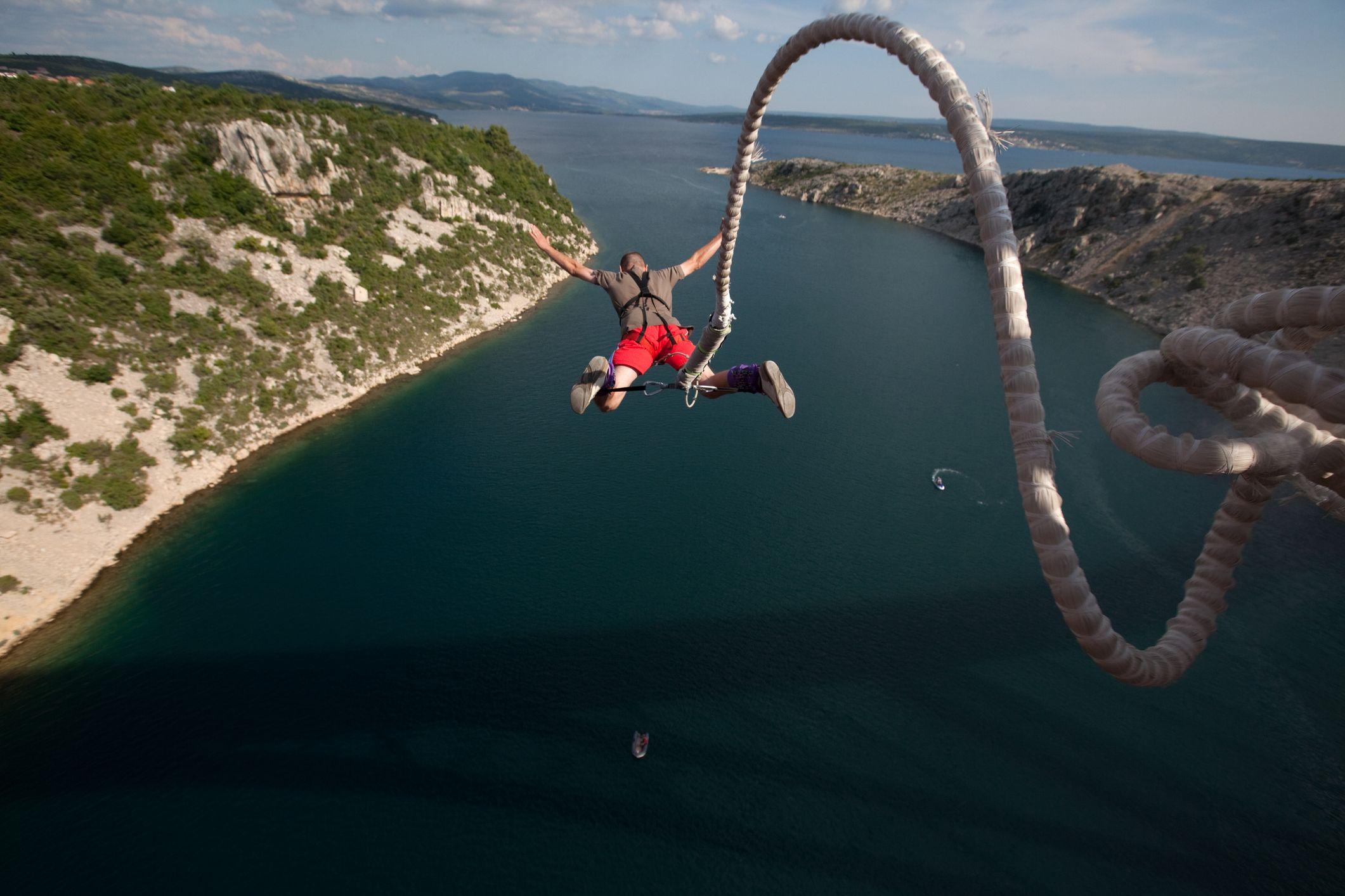 person bungee jumping above a river