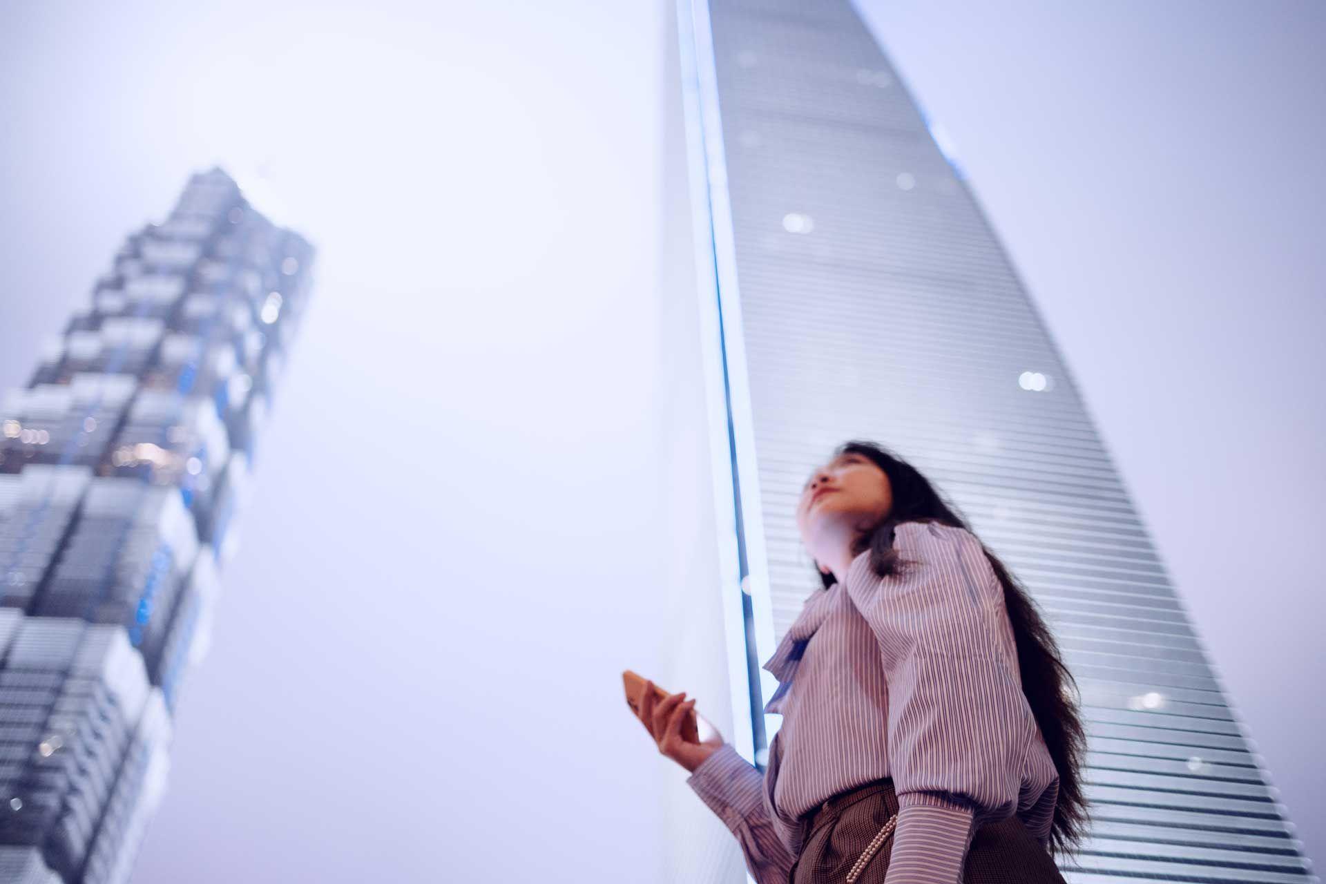 Woman with a phone in her hand between futuristic skyscrapers