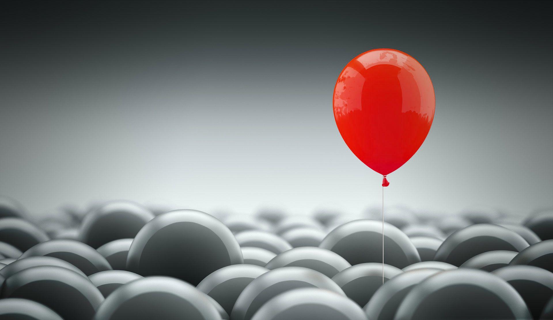 one red balloon emerging from a sea of grey balloons